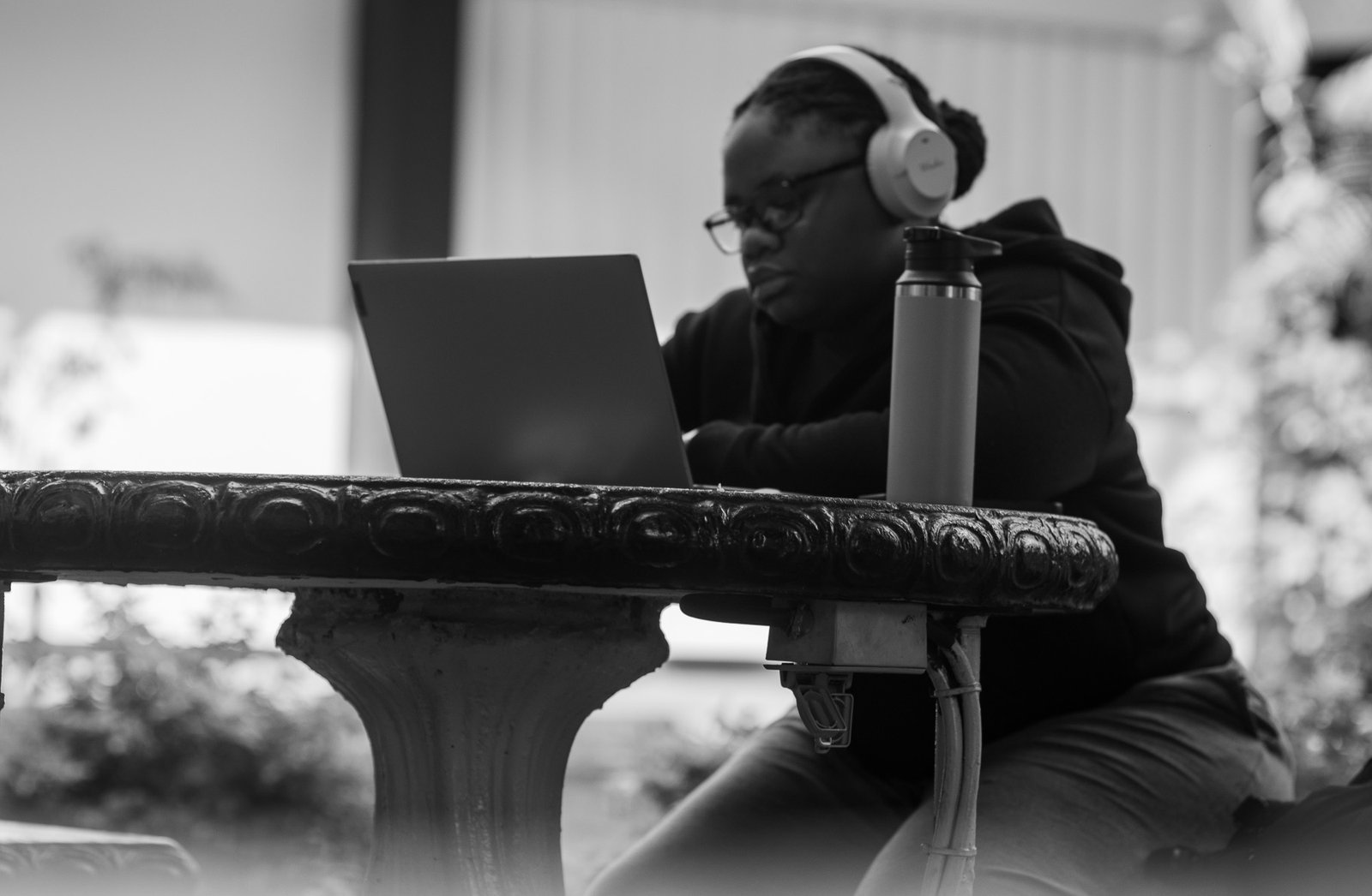 female sitting at a table with headphones and laptop